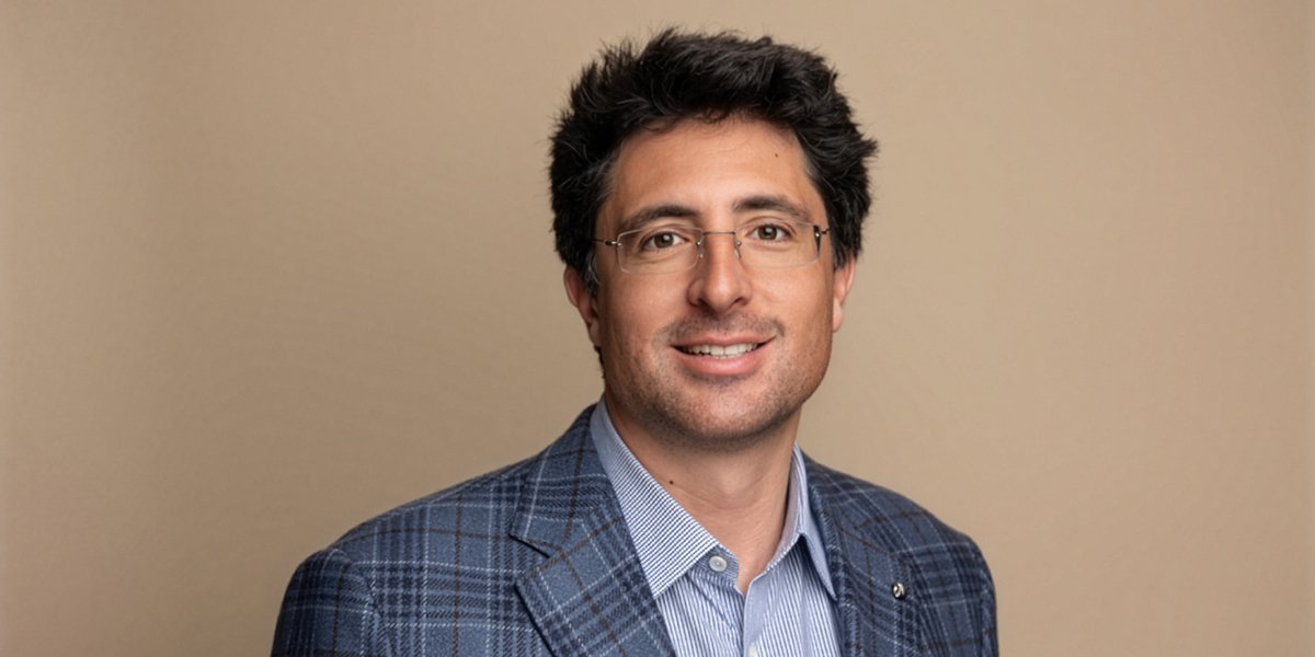 Niccolo de Masi posing for a photo against a light brown background.