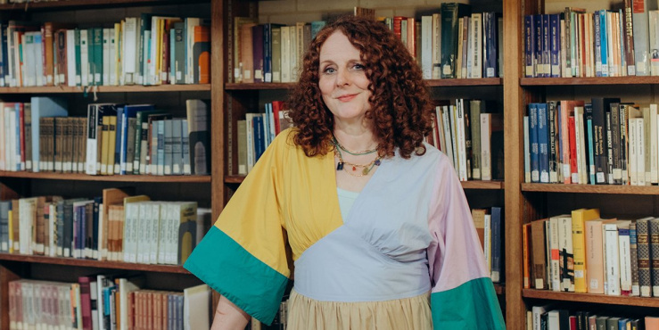 Maggie O'Farrell posing for camera in front of a library bookshelf.