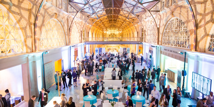 Photo of a large hall with people mingling amoungst dining tables