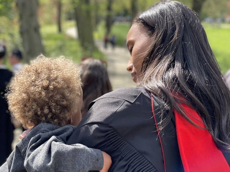 Anna Malaika Tubbs in a graduation gown holding a child