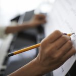 A writer composes music on a song sheet