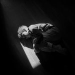 Black and white image of boy curled up on the floor