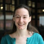 portrait photograph of Amelie Roper against a dark background wearing a blue top