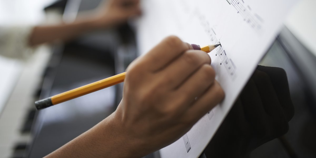 A writer composes music on a song sheet
